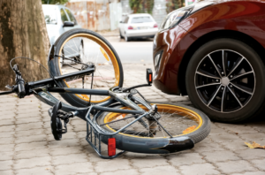 Bicycle lying on the sidewalk next to a car